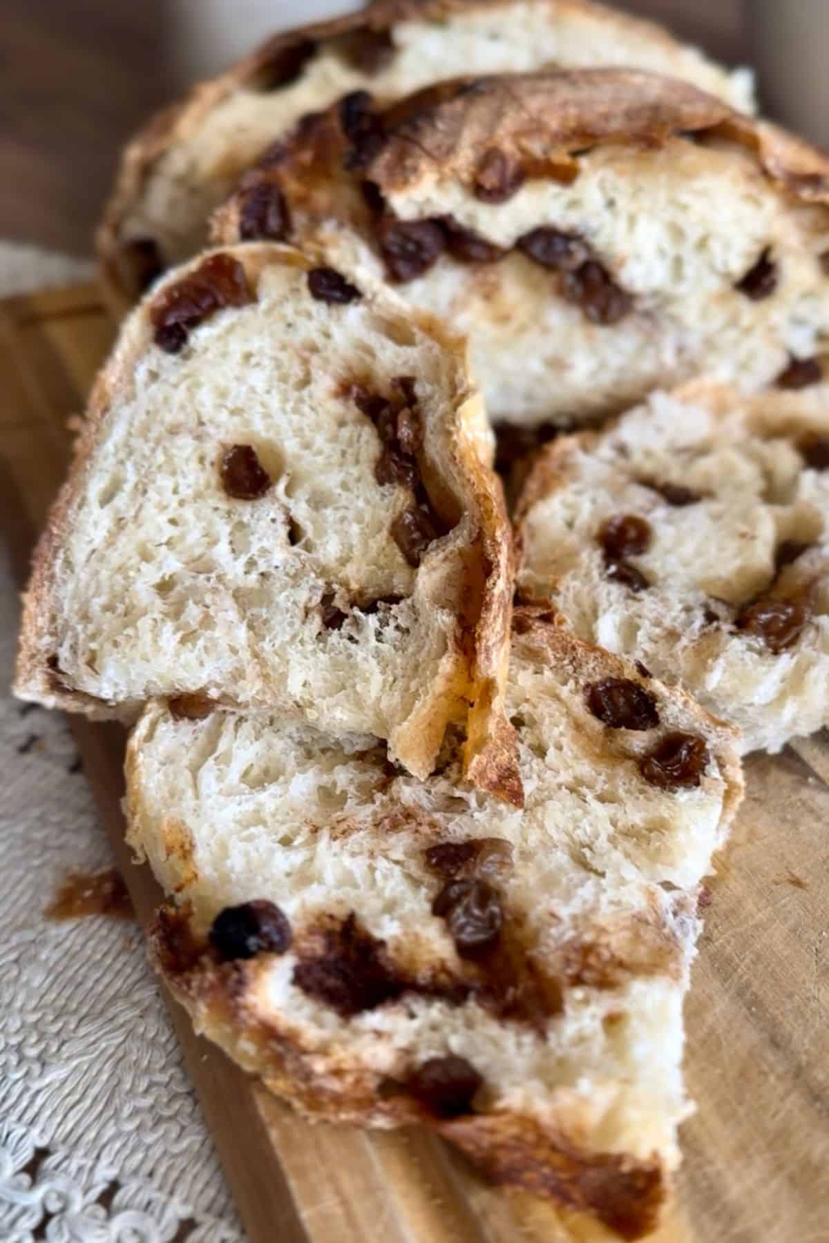 A slice of freshly baked bread on a wooden board, revealing its airy, soft interior; a knife rests beside it.