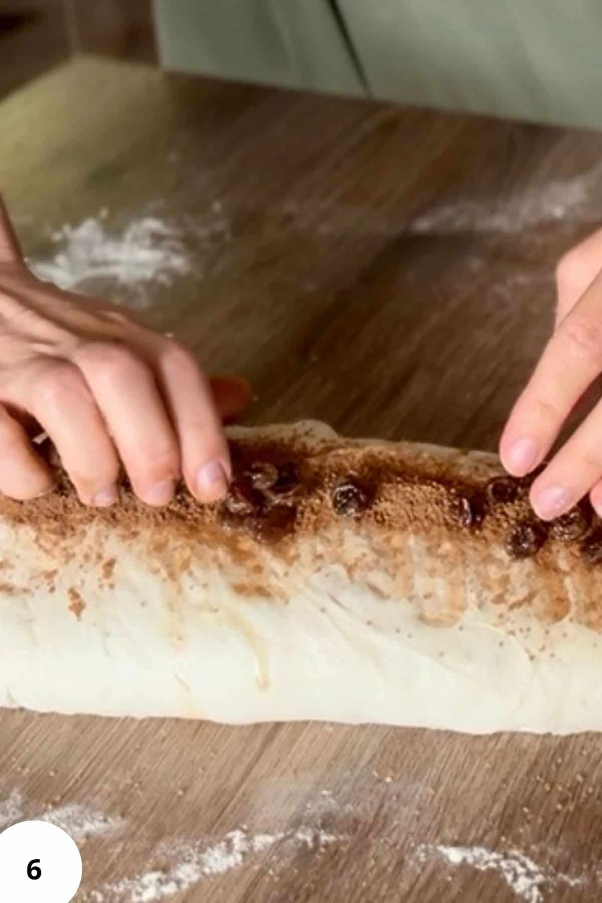 Person gently closing and shaping dough on a floured surface, preparing it for proofing.