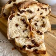 A slice of freshly baked bread on a wooden board, revealing its airy, soft interior; a knife rests beside it.