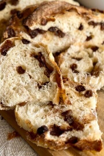 A slice of freshly baked bread on a wooden board, revealing its airy, soft interior; a knife rests beside it.