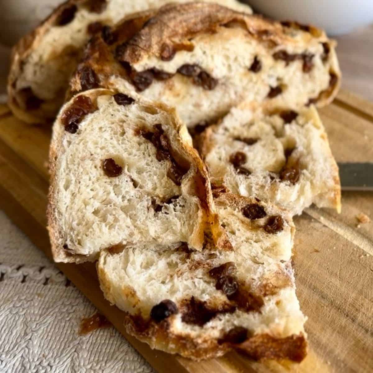 A slice of freshly baked bread on a wooden board, revealing its airy, soft interior; a knife rests beside it.