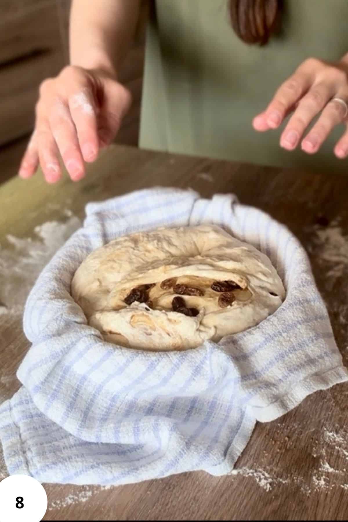 Person standing in front of a proofing basket with dough resting inside, lined with a cloth.