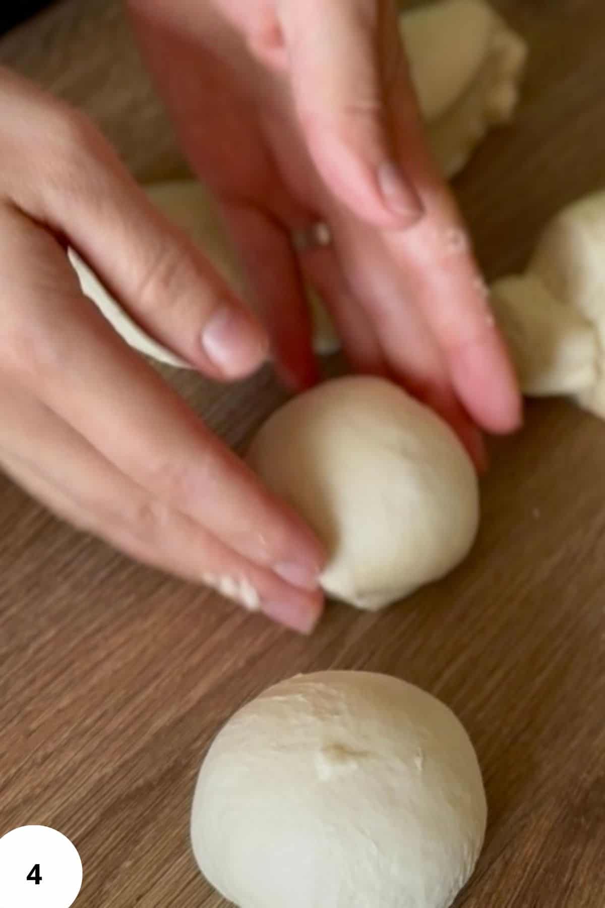 A hand placing each shaped bun onto a floured surface.