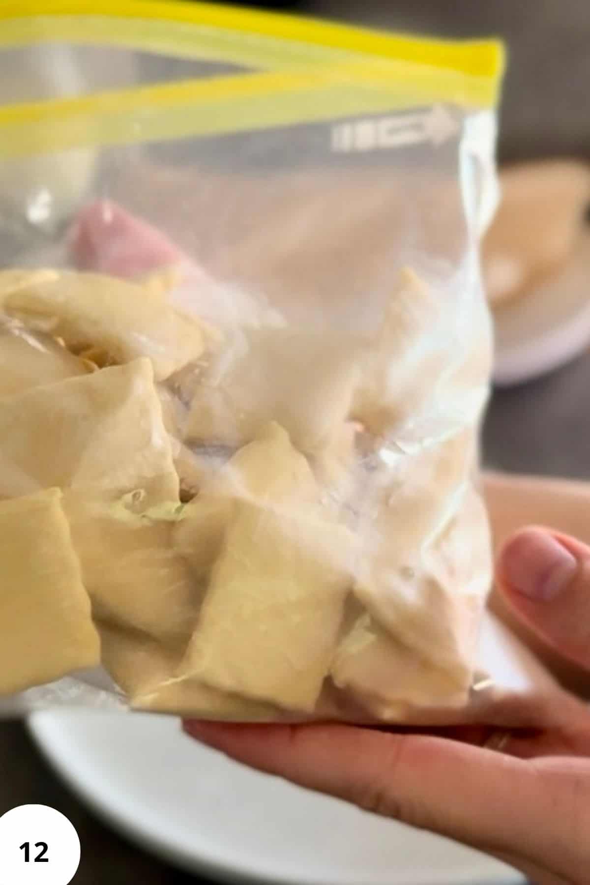 A ravioli being placed into a ziplock bag for storage or freezing.