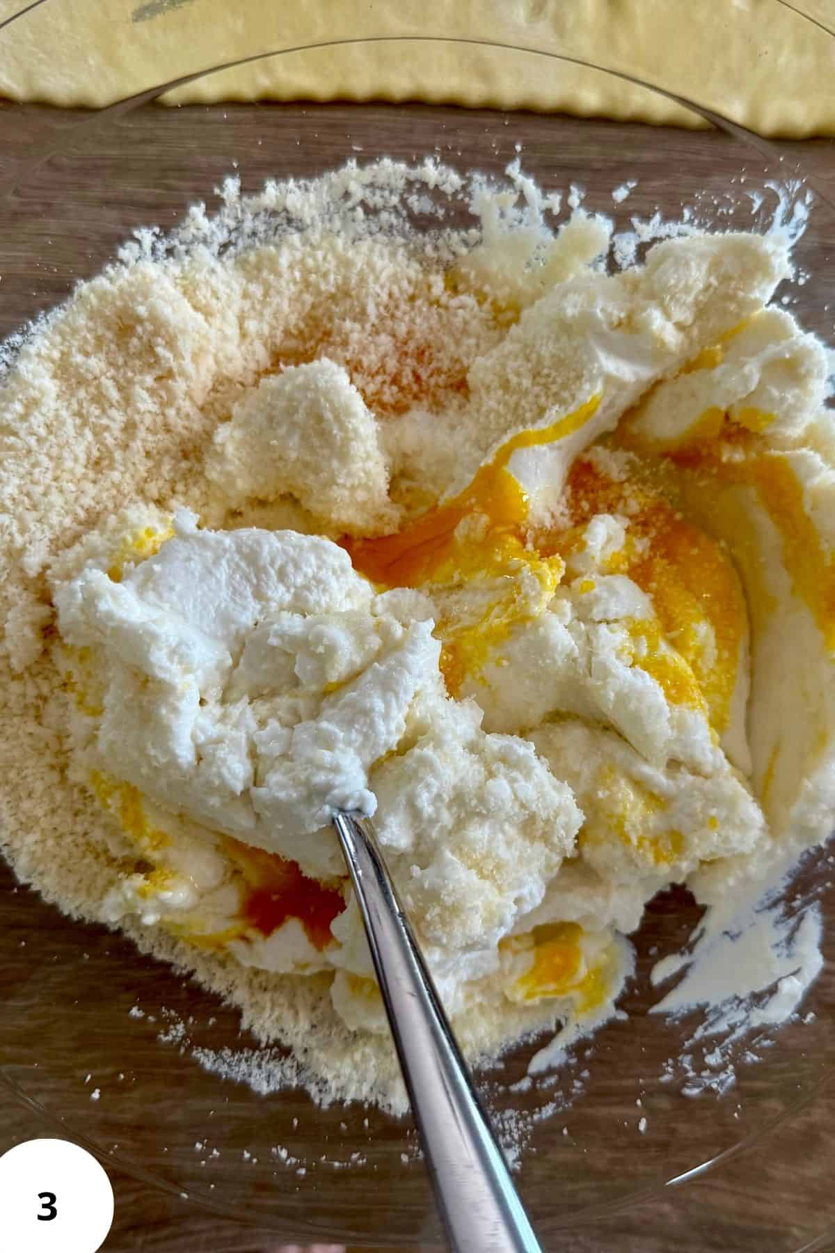 Ingredients being mixed together in a bowl using a spoon.