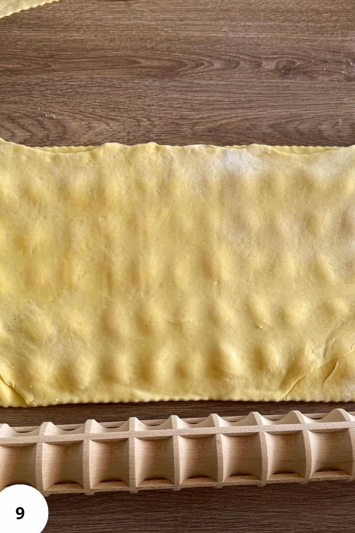 The sheet of dough being folded over to cover the ravioli filling.