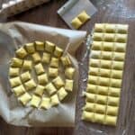 Ravioli arranged in a single layer on a parchment-lined tray.
