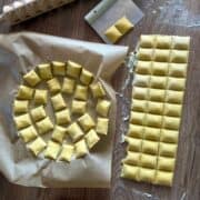 Ravioli arranged in a single layer on a parchment-lined tray.
