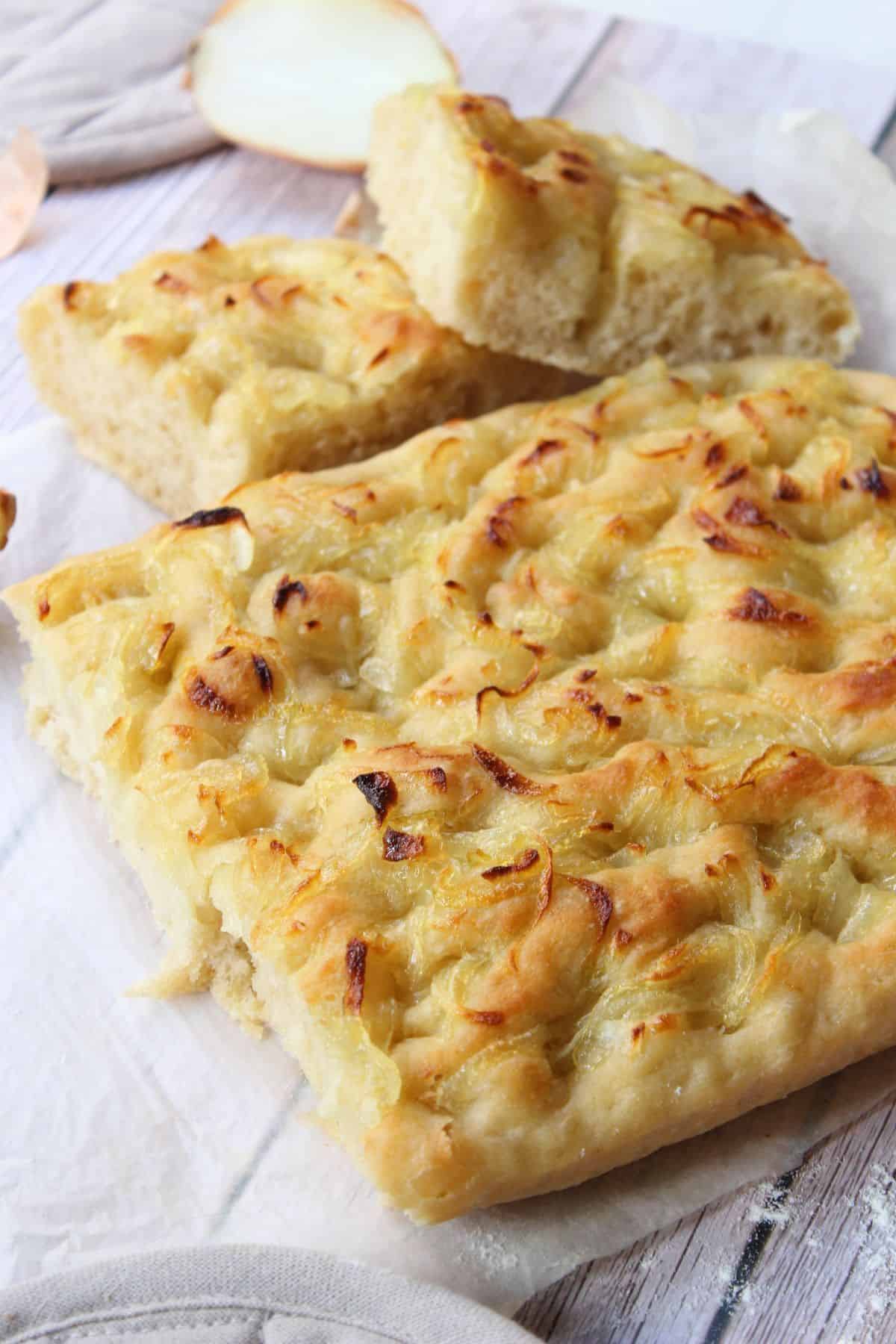 Sourdough focaccia resting on a flat surface, showing its golden crust and airy texture.
