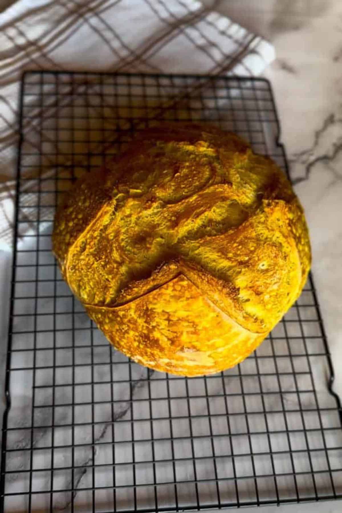 Freshly baked sourdough bread resting on a cooling rack.
