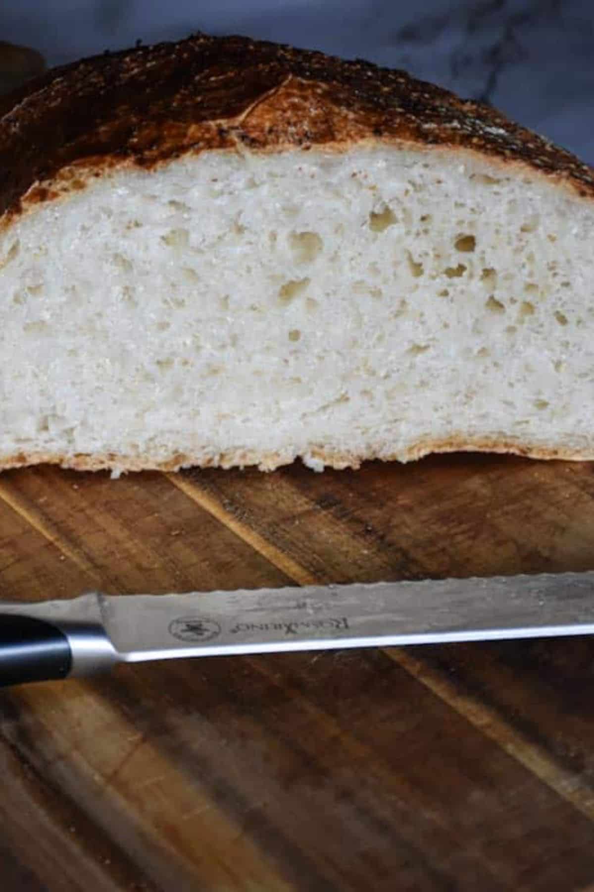 Close-up of sliced bread on a wooden board with a bread knife.