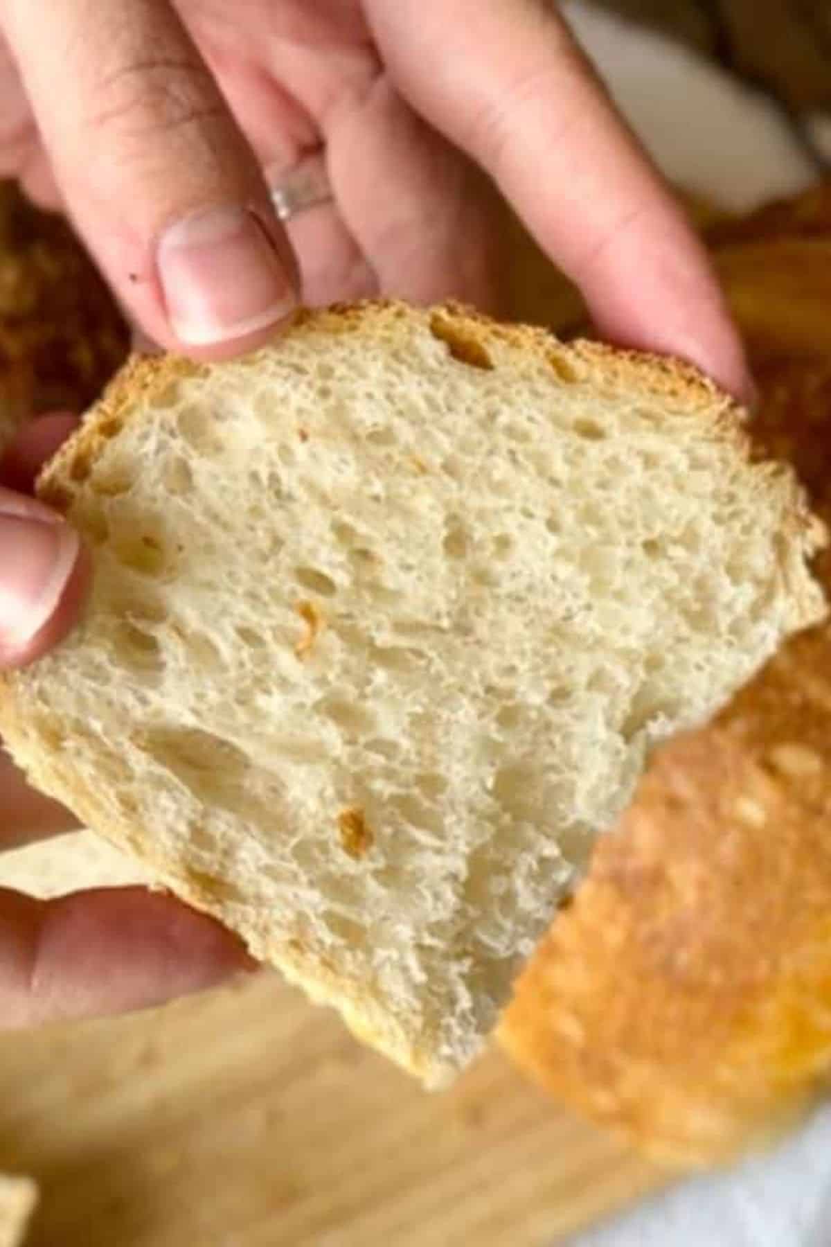 Person holding a single slice of bread, showing the soft interior.