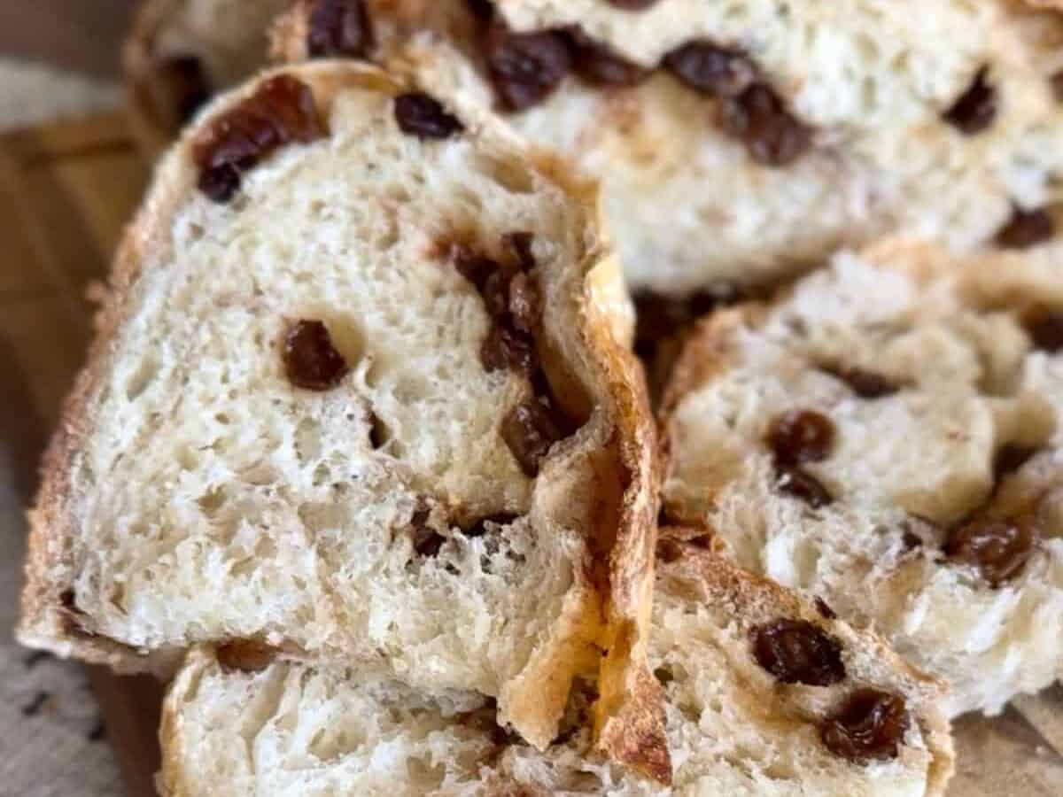A slice of freshly baked bread on a wooden board, revealing its airy, soft interior; a knife rests beside it.
