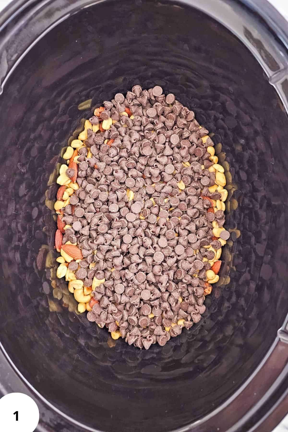 Ingredients for holiday crockpot candy including mixed nuts, chocolate chips, and white almond bark being placed in a Crockpot.
