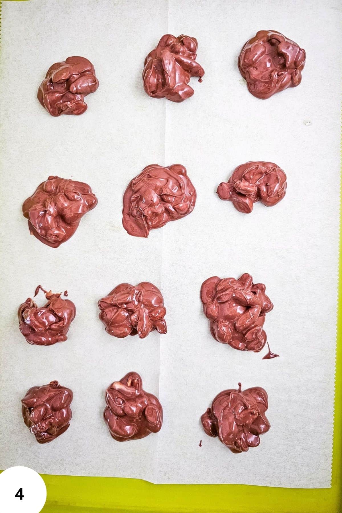 Dropping portions of melted chocolate onto parchment-lined baking sheets for holiday candy.