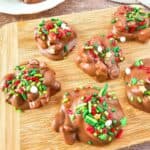 Crockpot holiday candy served on a wooden board with chocolate-coated and festive sprinkles.