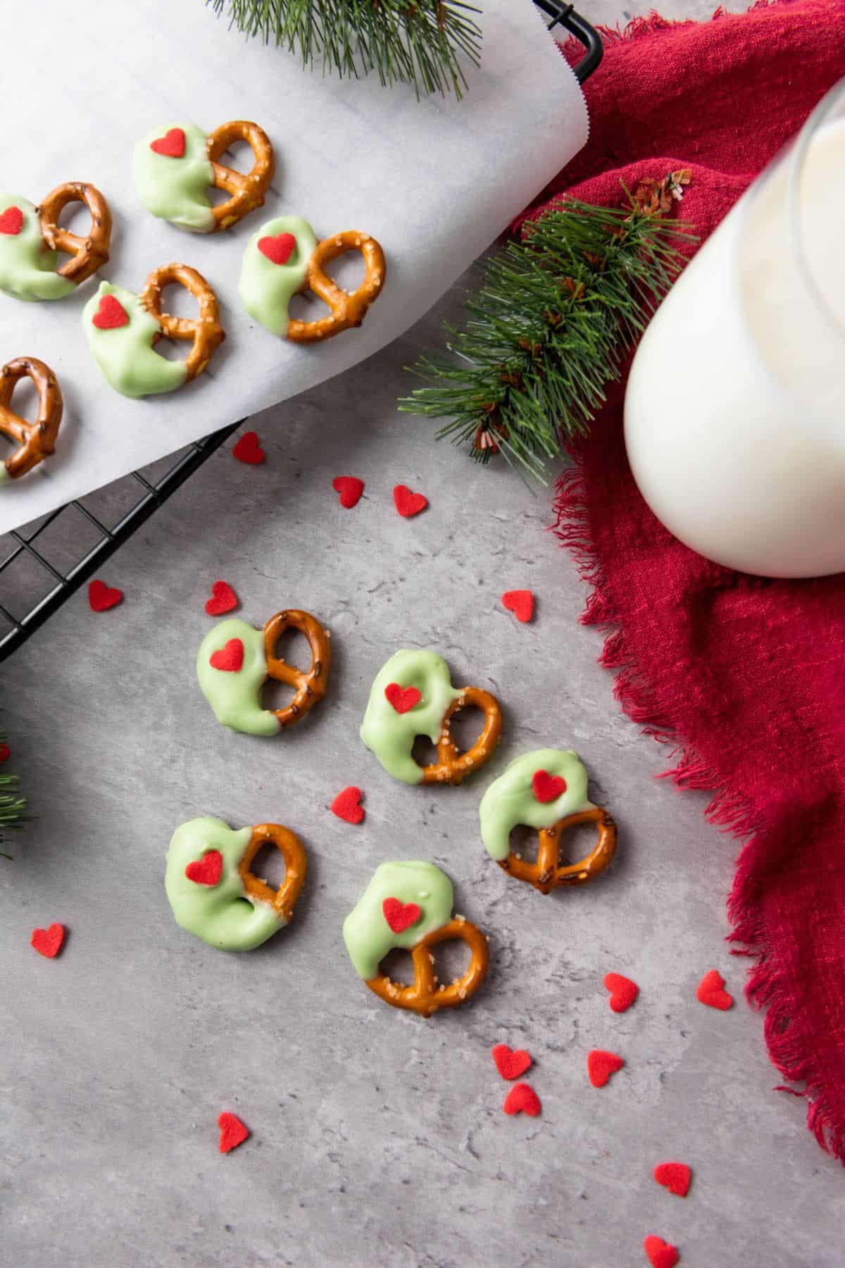 Christmas pretzels on a surface surrounded by heart sprinkles and a red cloth.