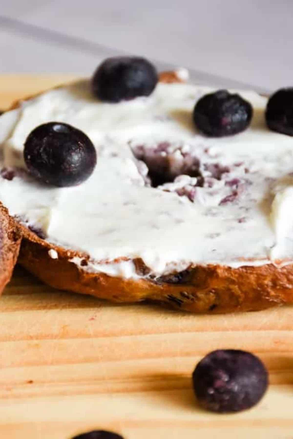 Blueberry bagels topped with fresh blueberries, surrounded by frozen blueberries for a frosty contrast.