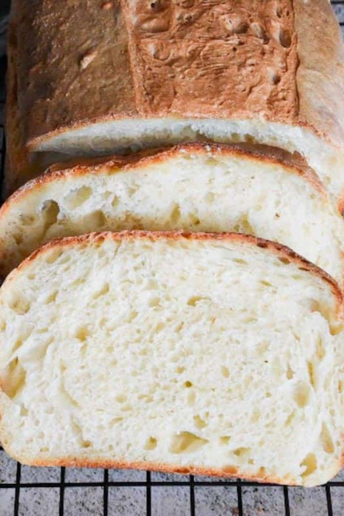 Sliced sandwich bread made with milk cooling on a wire rack, showing soft, even-textured slices.