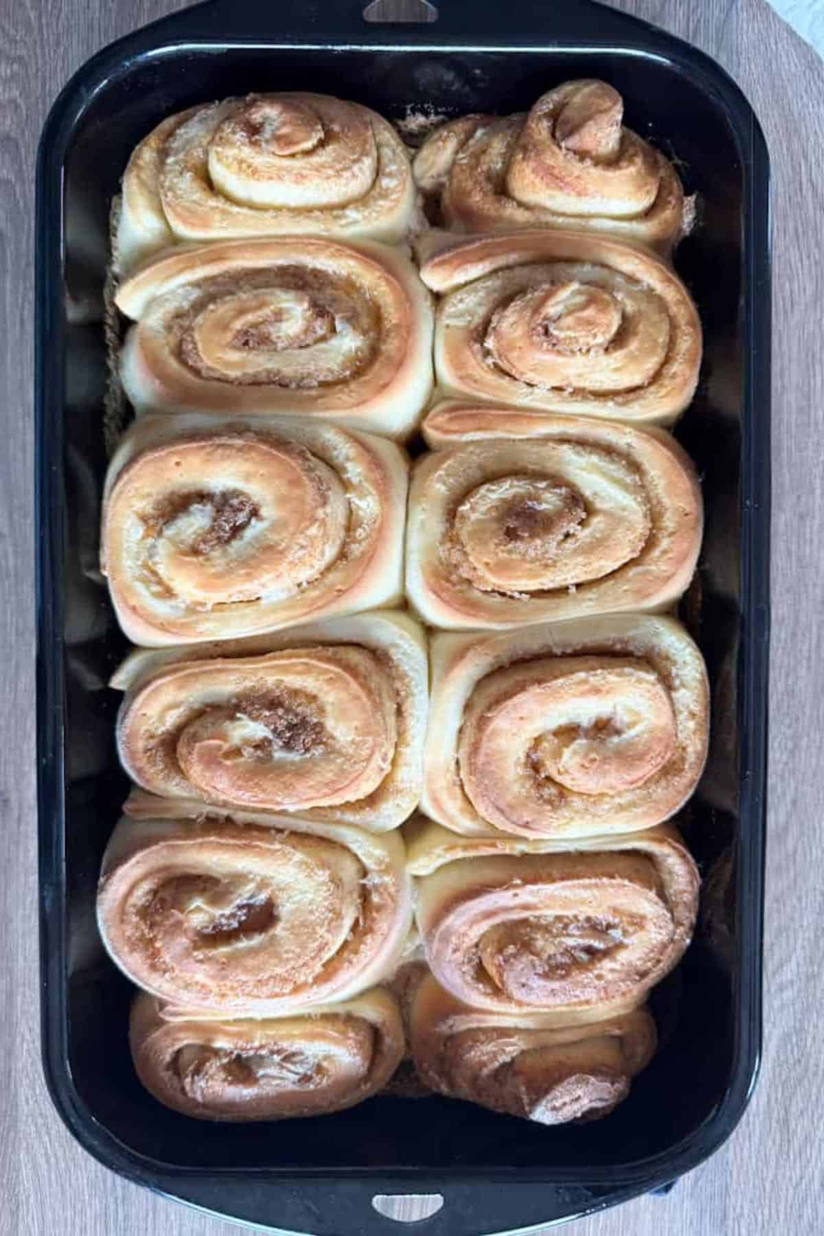 Warm cinnamon rolls in a baking pan, golden-brown with swirls of cinnamon.
