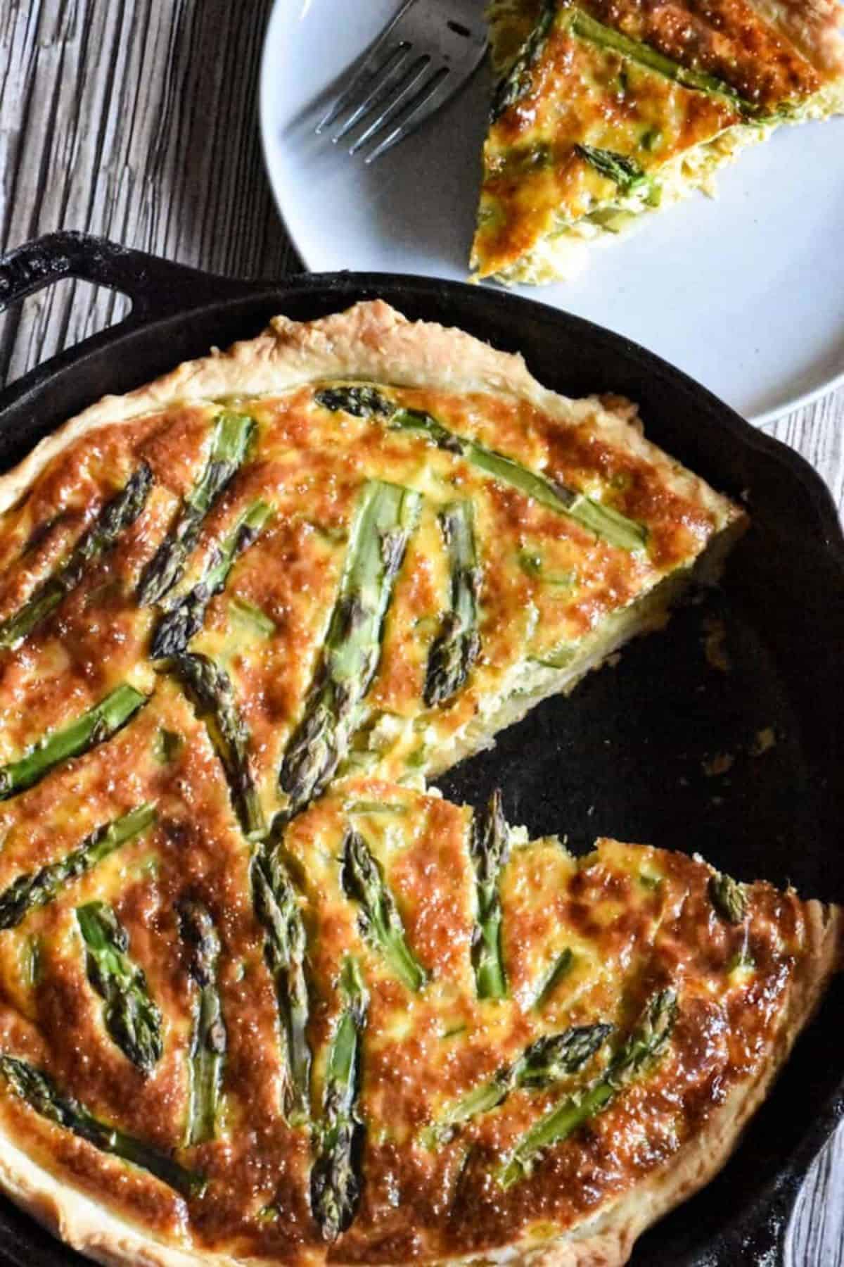 Sourdough quiche in a skillet with a slice being cut, showing a golden crust and creamy filling.