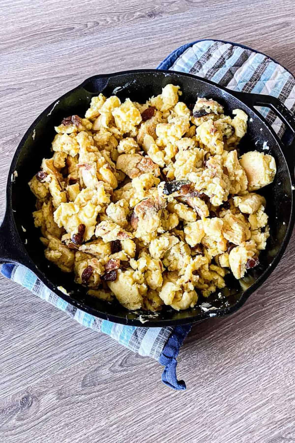 Sourdough Kaiserschmarrn in a black skillet, golden and fluffy with crispy edges, placed on a light-colored cloth underneath.