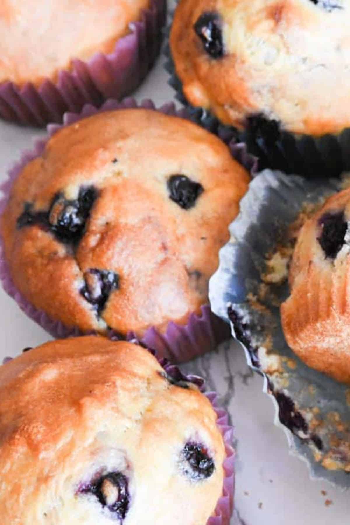 “Sourdough discard blueberry muffins arranged on a flat surface, with visible juicy blueberries throughout.
