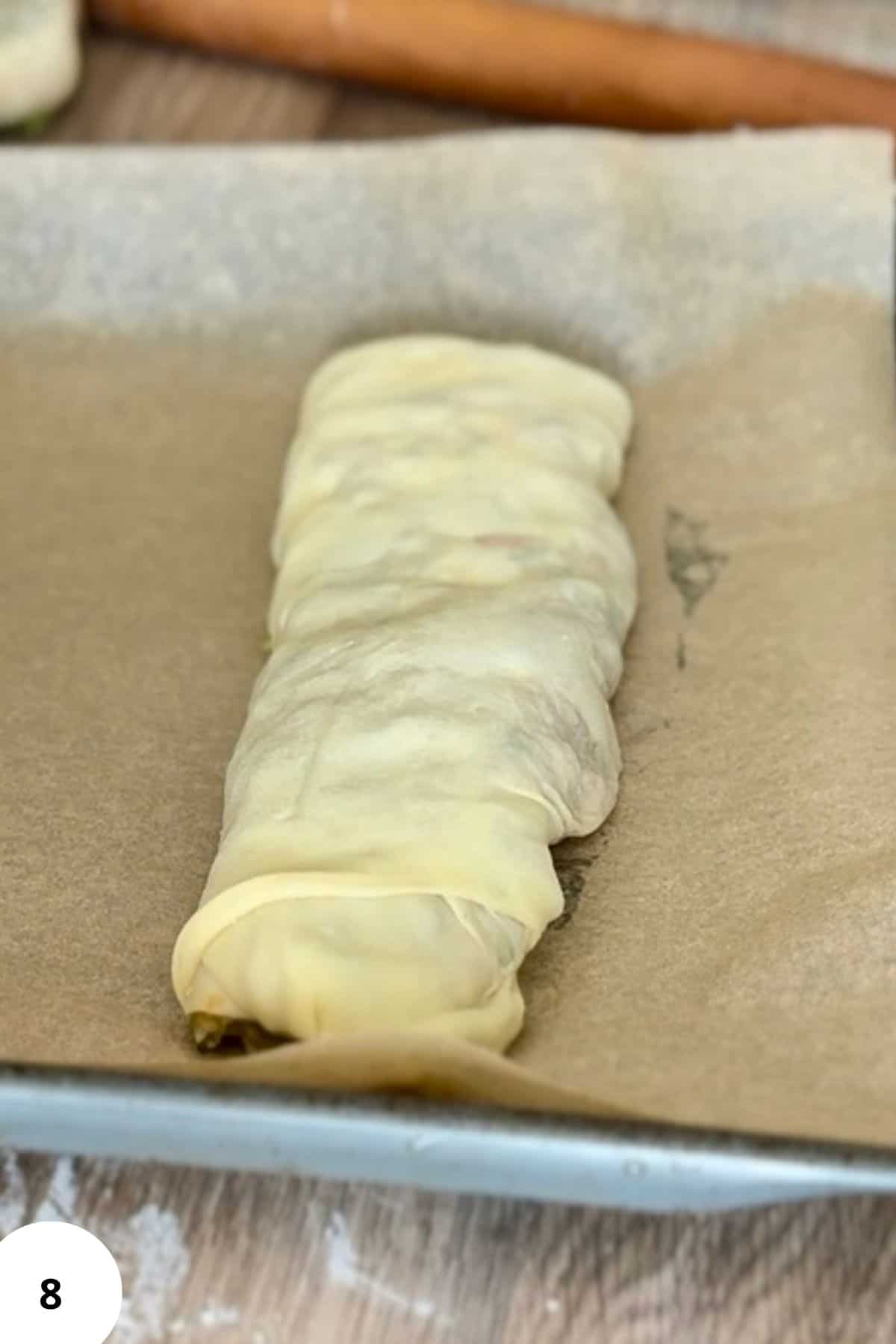 log of strudel placed on parchment paper, ready for baking.