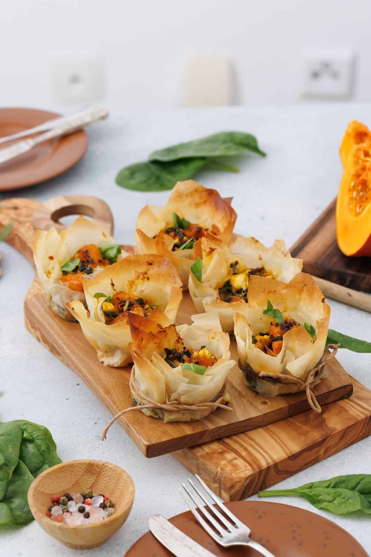 Pumpkin feta phyllo cups served on a wooden board.