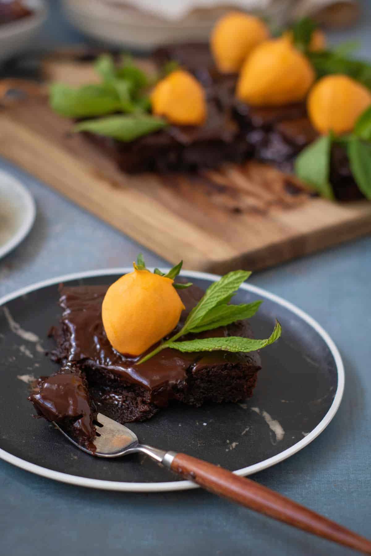 Sliced of chocolate pumpkin patch brownie cake served on a plate, with more slices in the background on a wooden board.