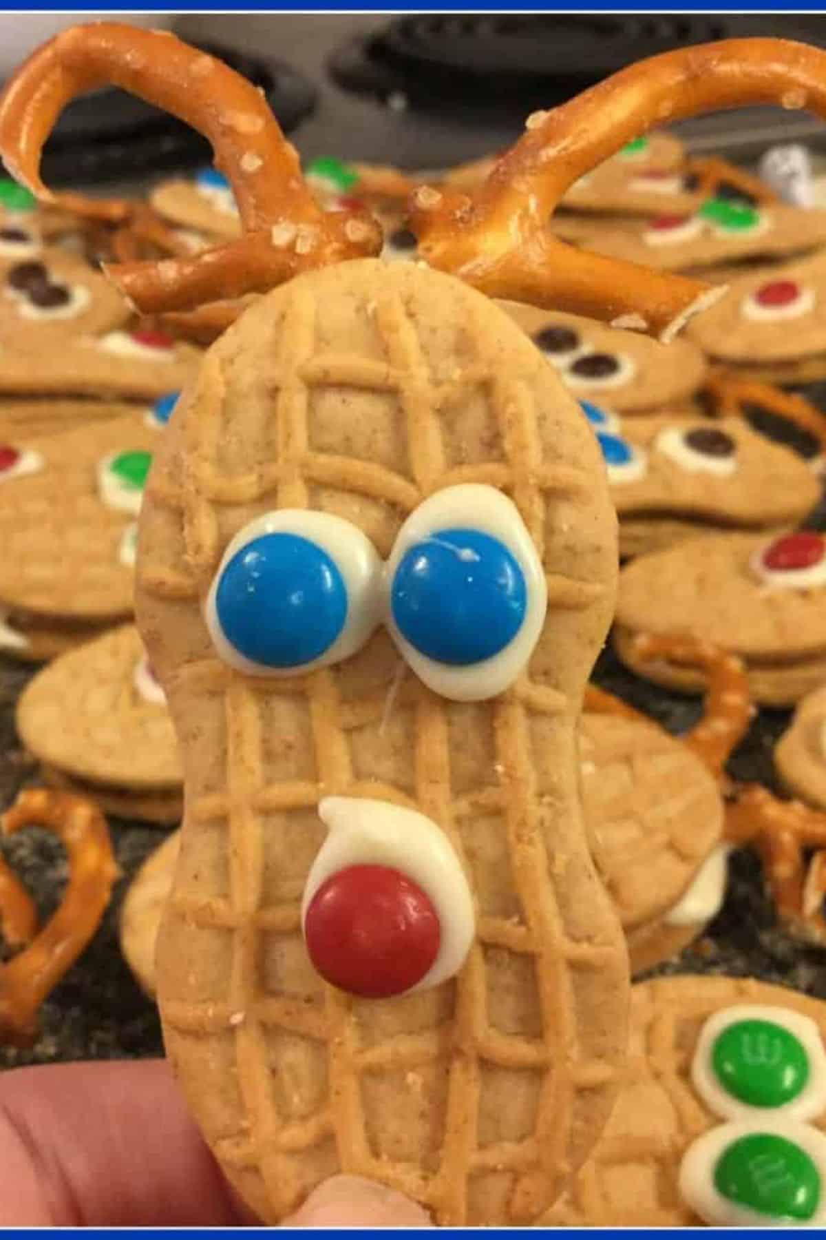 Nutter Butter Reindeer Cookie decorated with candy eyes and pretzel antlers.