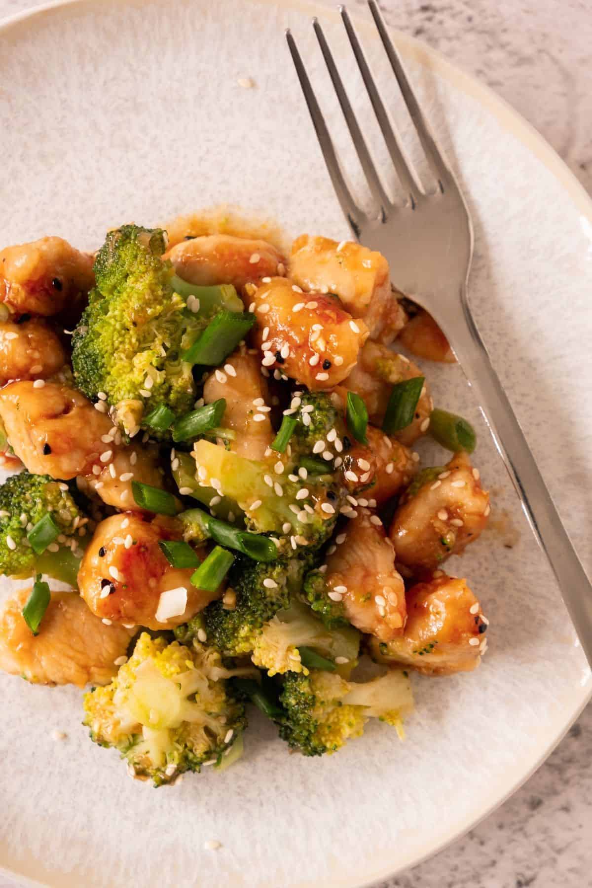 Honey Garlic Chicken with Broccoli served on a plate with a fork placed on the side.