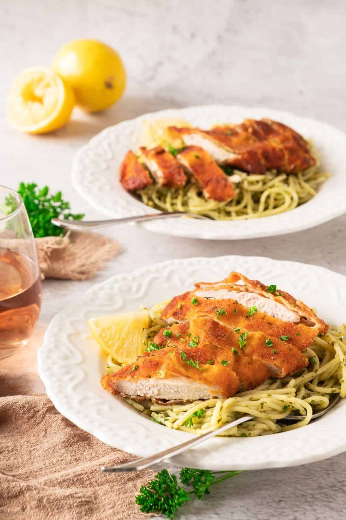 Two plates of Crispy Lemon Garlic Chicken with Spaghetti, each topped with golden chicken and folded pasta.