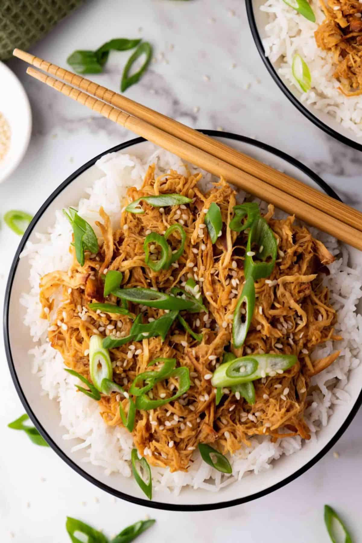 Crockpot Slow Cooker Soy Honey Garlic Chicken served with rice in a bowl, chopsticks resting on the side.