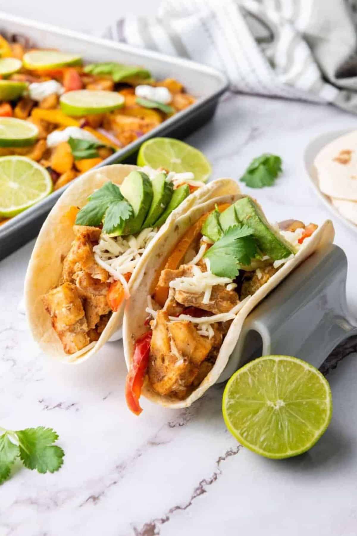 Sheet Pan Chicken Fajitas served in a holder, garnished with lime slices and fresh parsley.