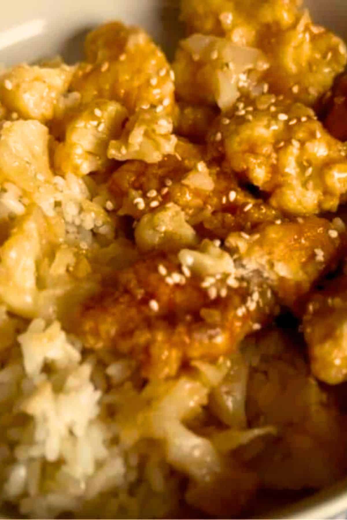 Close-up of Crispy Fried Sweet and Sour Chicken with Cauliflower served over rice, showing the golden chicken coated in sauce and tender cauliflower pieces.