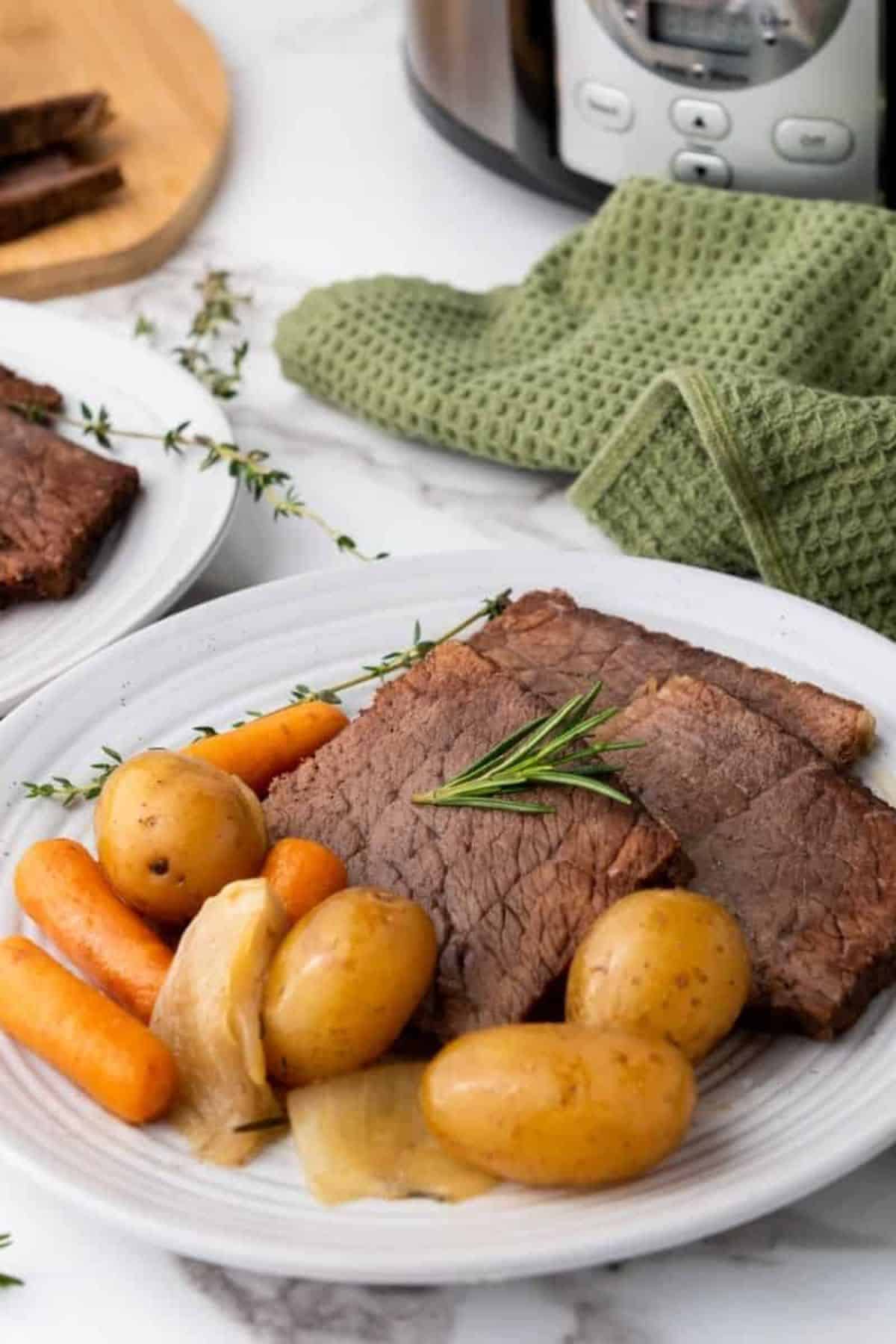 Crockpot Slow Cooker Rump Roast served on a plate with vegetables on the side.