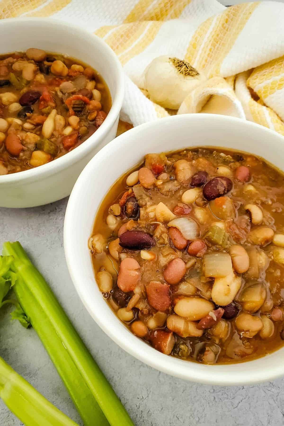Two bowls of Crockpot Vegan Bean Soup filled with beans and vegetables.