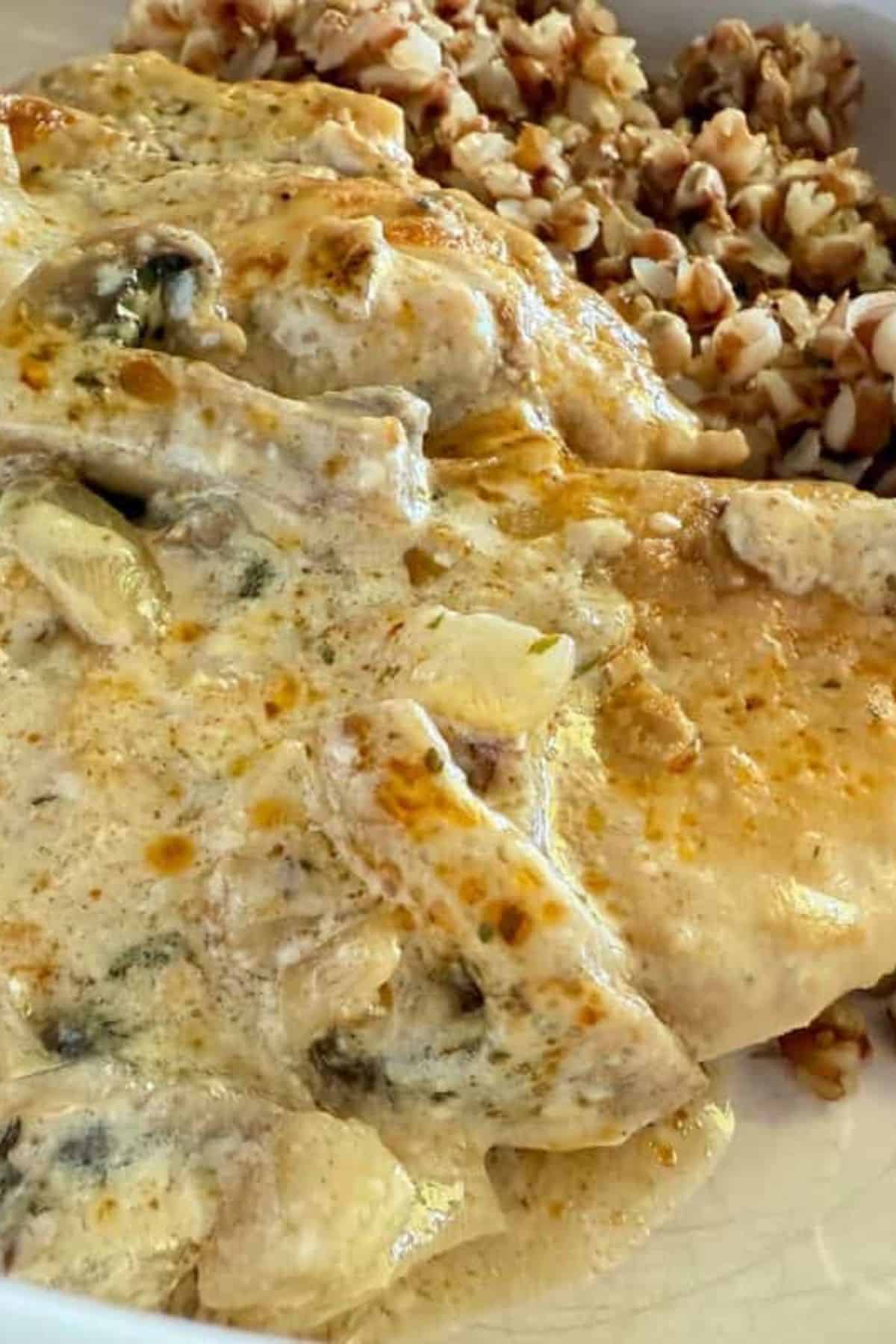 Close-up of chicken in creamy mushroom sauce with buckwheat groats served in a pan.