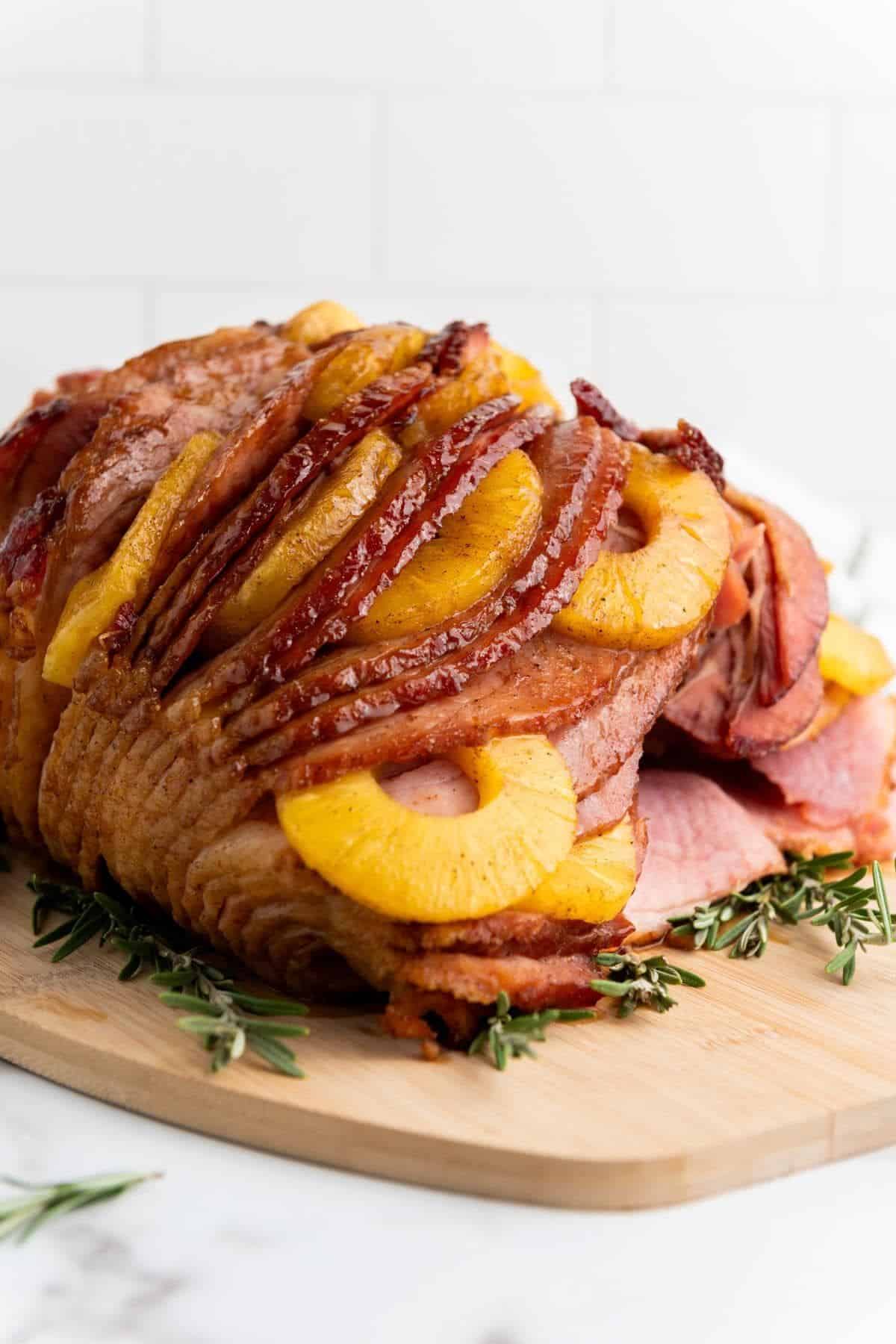 Brown Sugar Pineapple Ham served on a wooden board with caramelized pineapple on top.