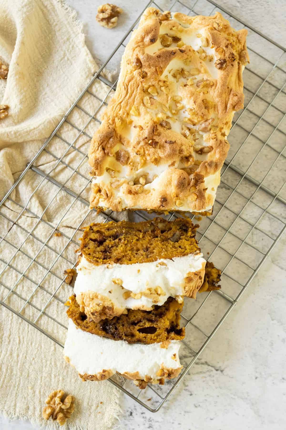 Sweet Potato Quick Bread with Fluffy Meringue being sliced while resting on a wire cooling rack.