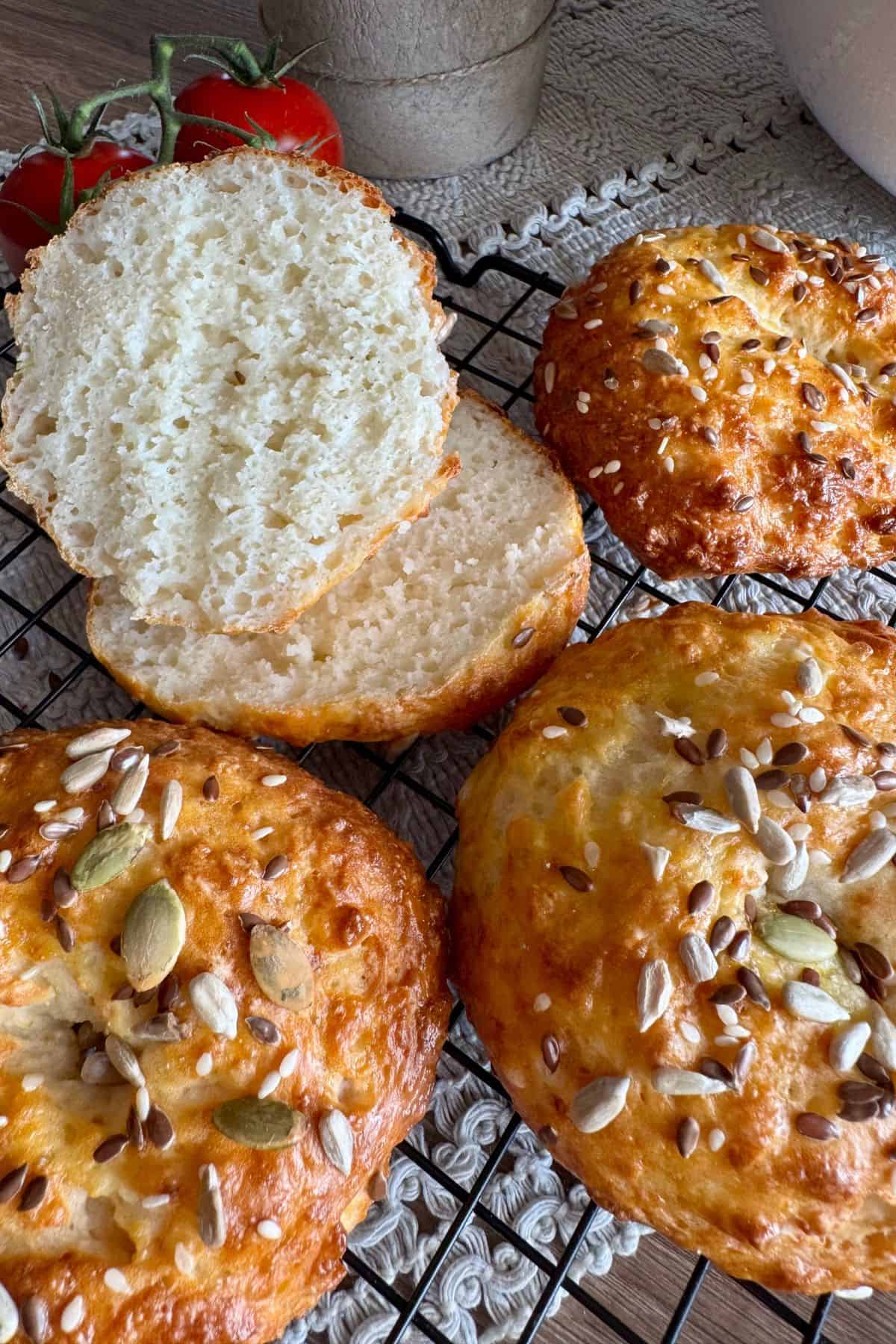 Greek Yogurt Protein Bagels in a wire cooling rack, with one being sliced to show the soft, airy interior.