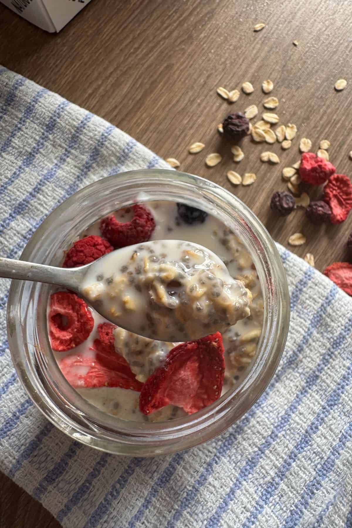 Spoon lifting a portion of blueberry oatmeal, showing the creamy texture and blueberries.