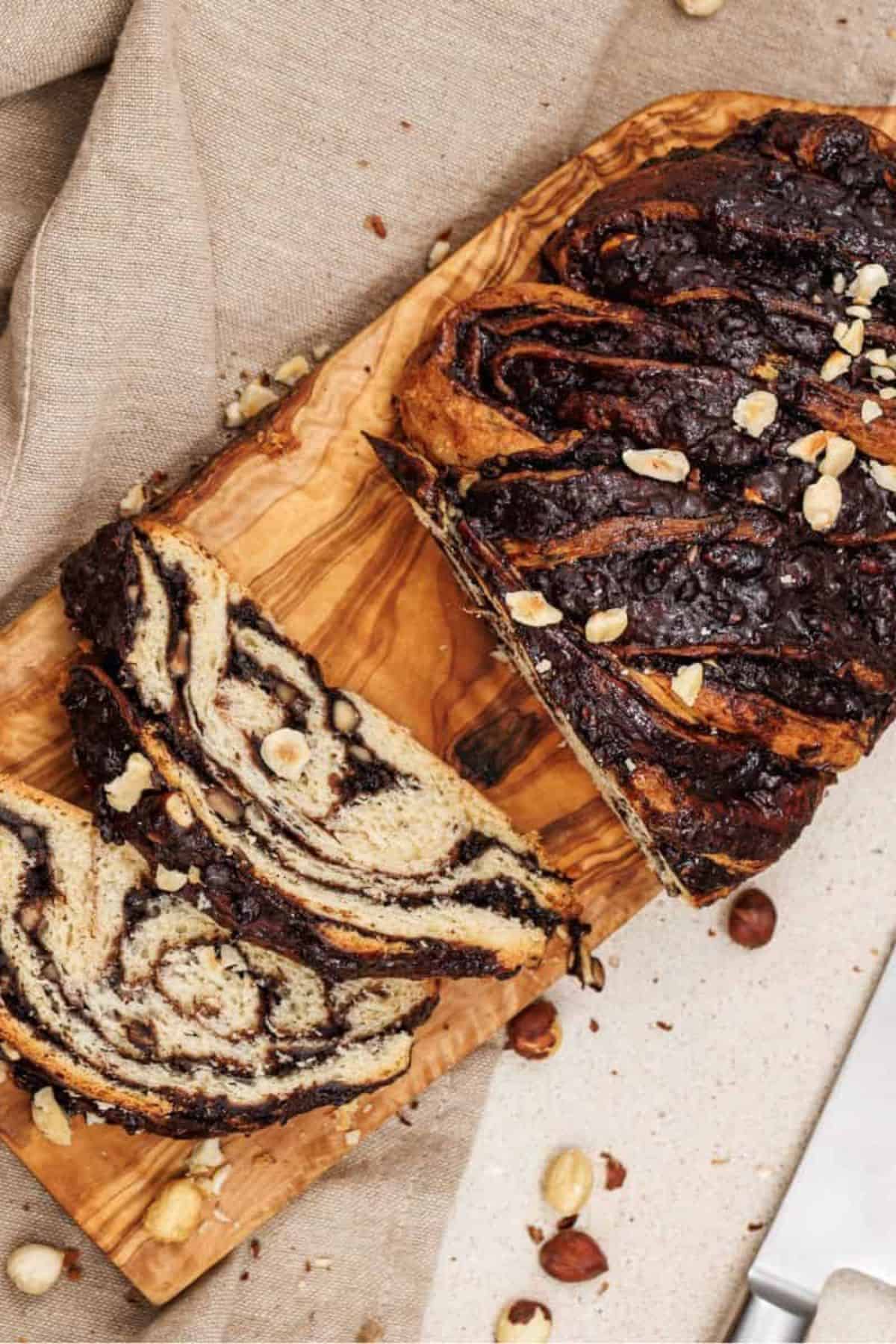 Chocolate hazelnut babka loaf with slices arranged on a wooden board.