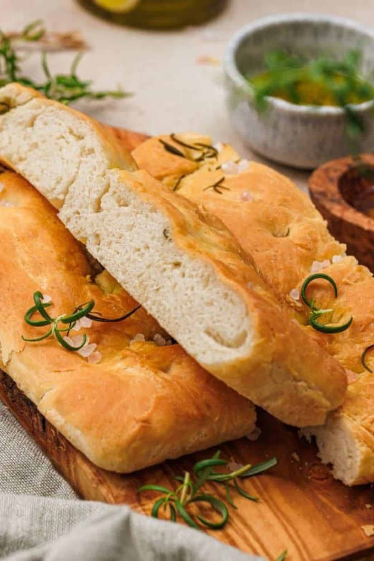 Sliced rosemary and sea salt focaccia topped with fresh rosemary sprigs.