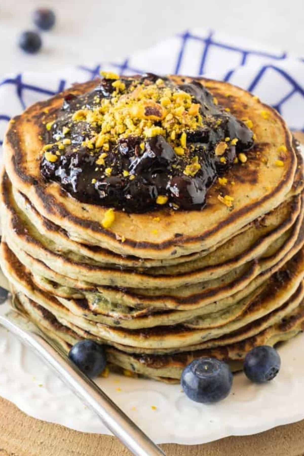 Stack of pancakes topped with blueberry jam and fresh blueberries on the side.