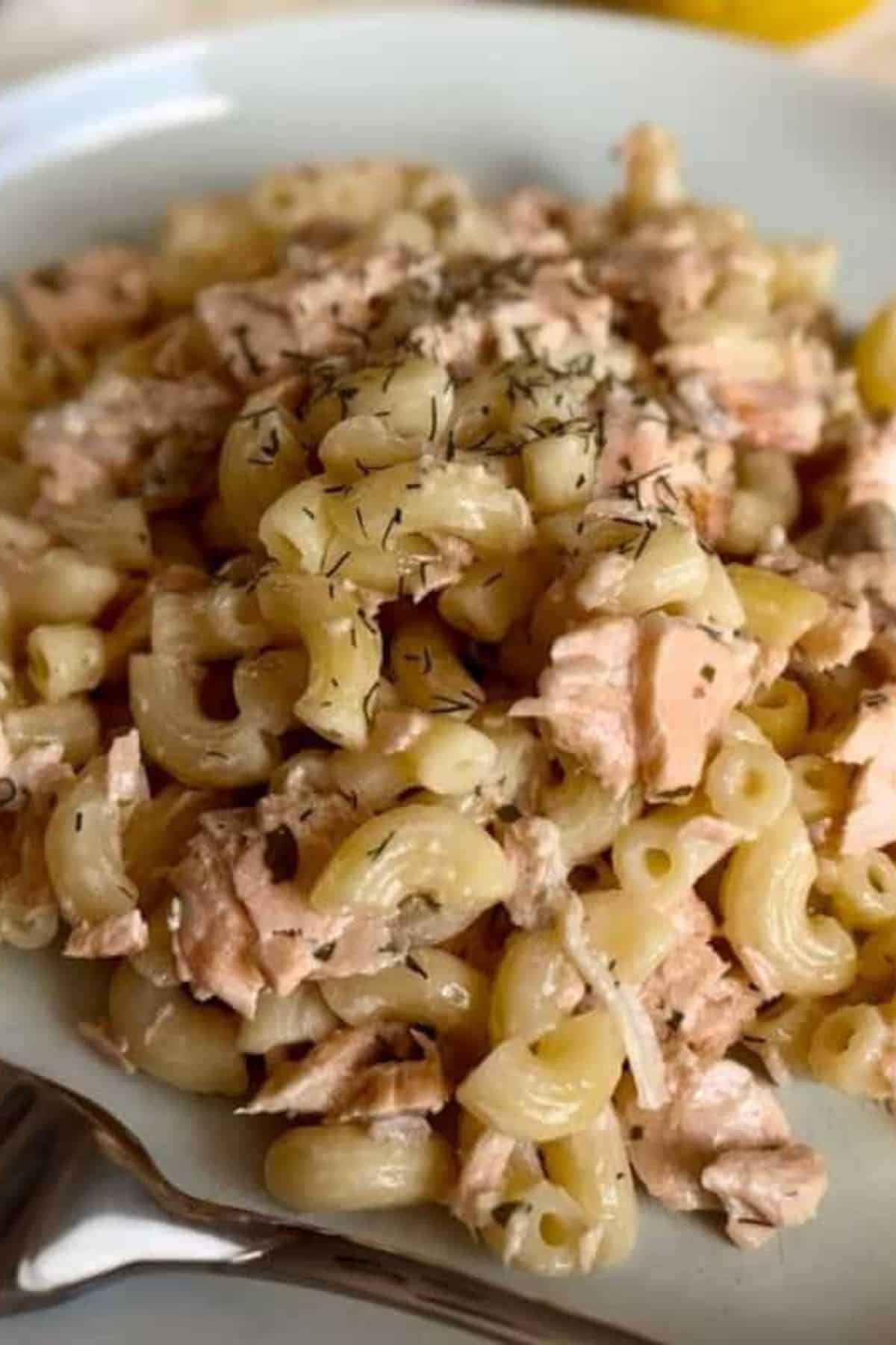 A plate of creamy dill salmon pasta with a fork resting on the side.