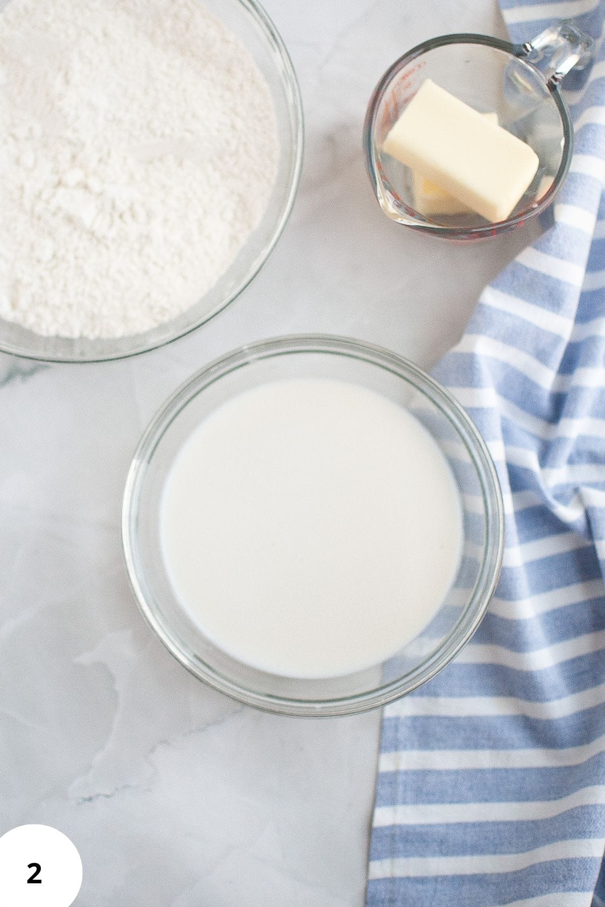 Wet ingredients being mixed in a large bowl with other ingredients placed around it.