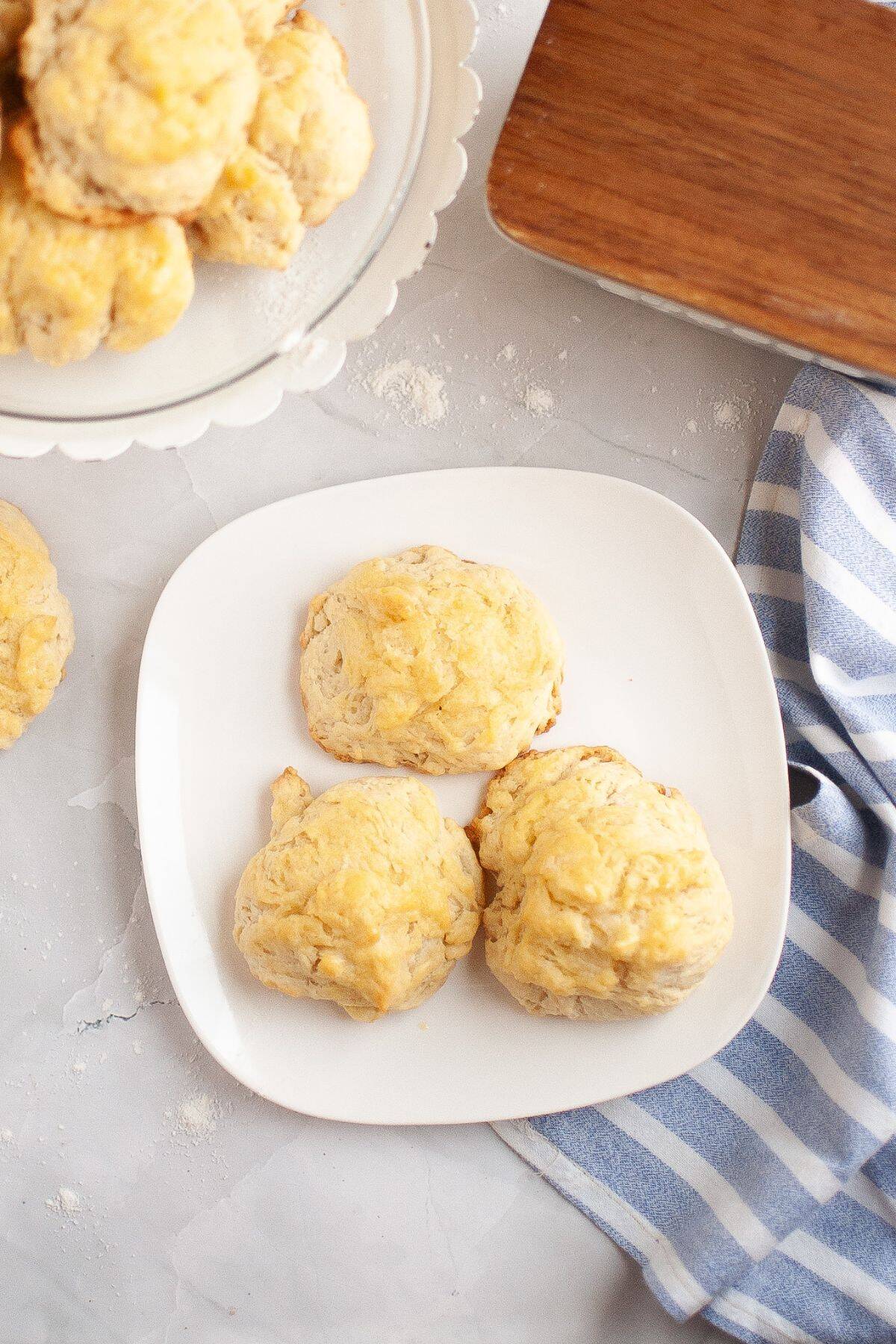 Three muffins served on a plate, with a cloth napkin placed beside them.