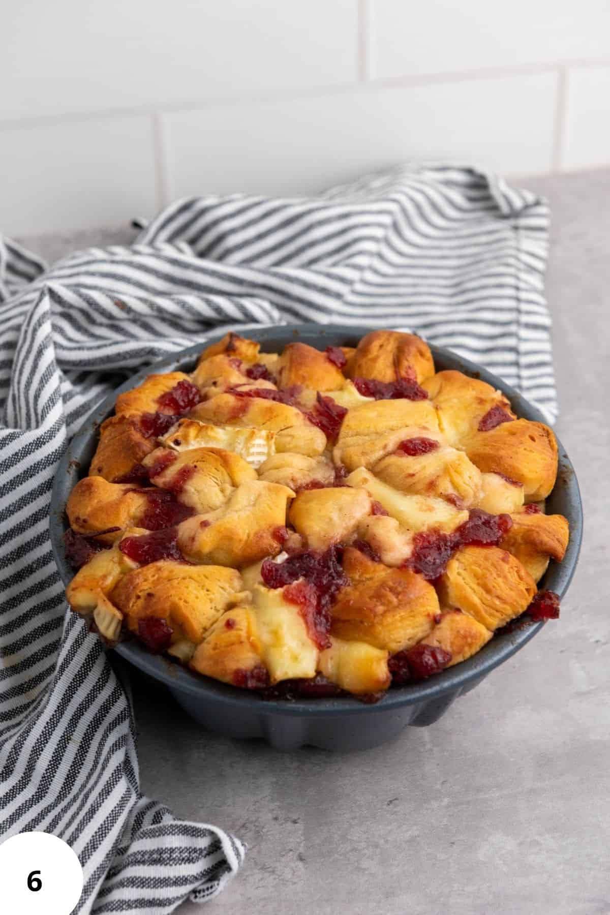 Freshly baked bread resting in a mixing bowl with a cloth underneath.